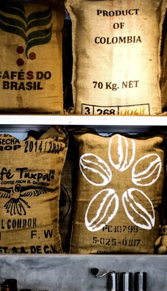Jute sacks of green coffee from Colombia, Brazil and El Salvador stacked on shelves