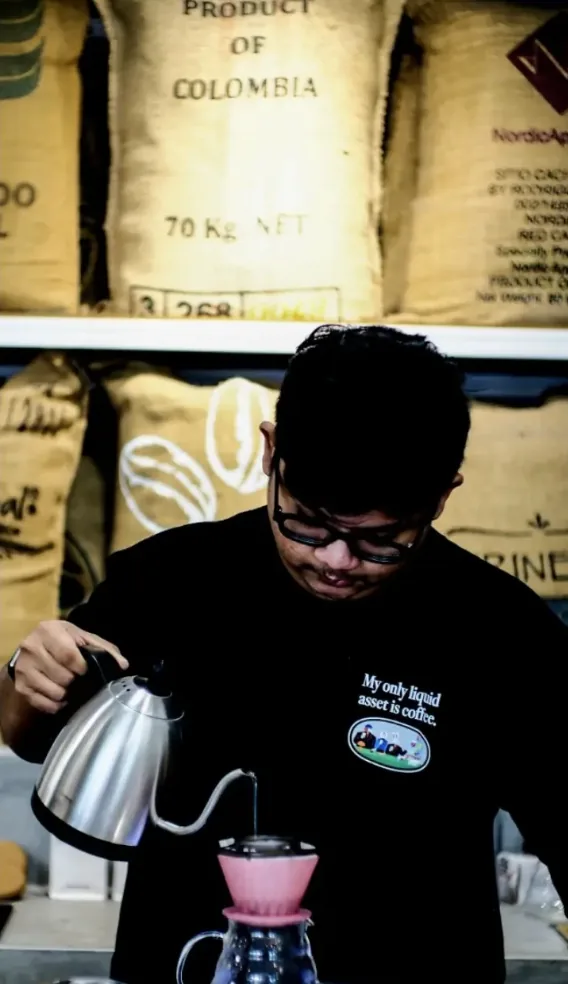 Barista pouring a filter coffee into a pink dripper